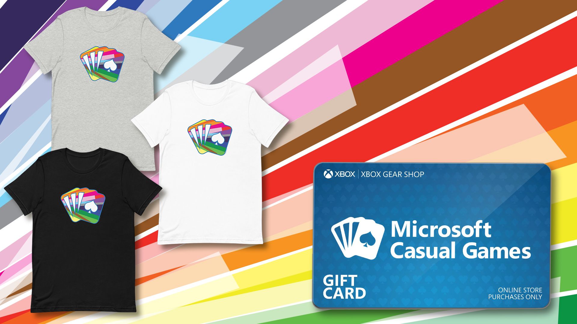 The background is filled with angled rays of colors. 3 t-shirts are displayed on the left in black, grey, and white with the new Microsoft Causal Games pride logo. An Xbox Gear Shop gift card is on the right.
