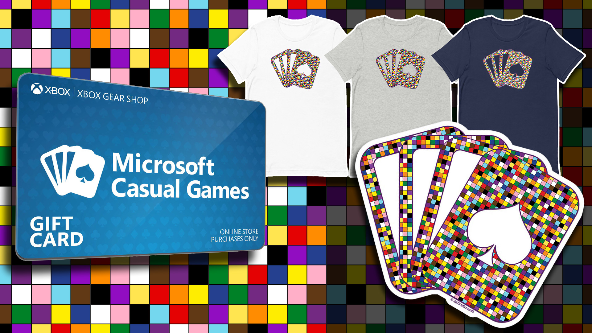 The background is covered with colorful checkered squares. A Microsoft Casual Games vinyl sticker and 3 t-shirts with the 2023 Pride design displayed on the right in white, grey, and navy blue. An Xbox Gear Shop gift card is on the left.